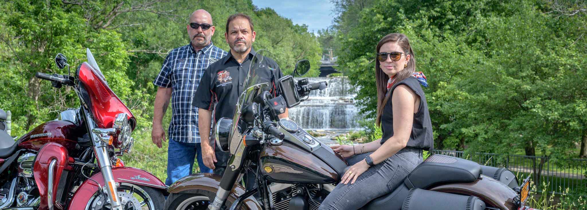 Marketing guy Chris Genovese, attorney and founder Steve Kantor, and attorney and partner Christina Gullo with two Harley-Davidson motorcycles in front of Glen Falls in Williamsville, NY