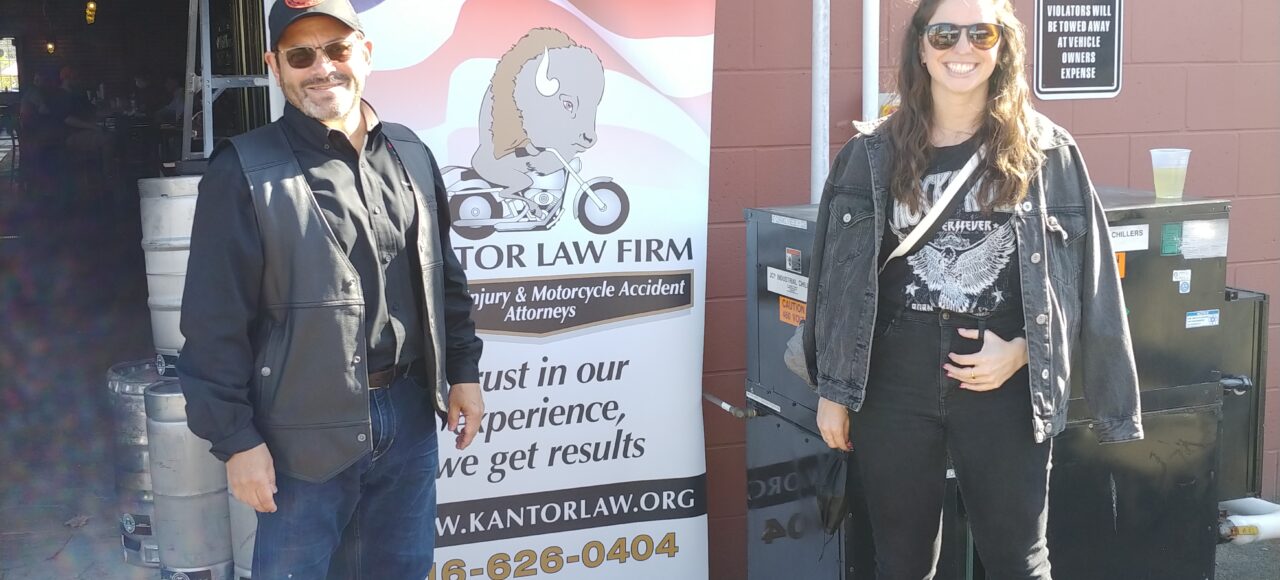Attorneys Steve Kantor and Christina Gullo of the Kantor Gullo Law Firm stand in front of one of the firm's banners at a Bike Night event