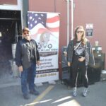 Attorneys Steve Kantor and Christina Gullo of the Kantor Gullo Law Firm stand in front of one of the firm's banners at a Bike Night event