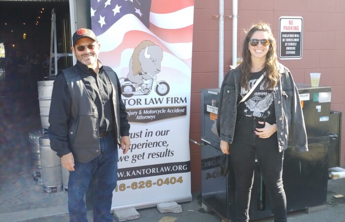 Attorneys Steve Kantor and Christina Gullo of the Kantor Gullo Law Firm stand in front of one of the firm's banners at a Bike Night event