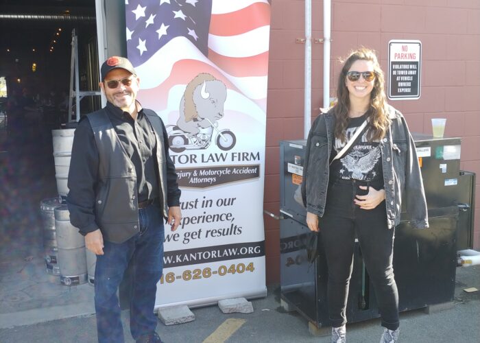 Attorneys Steve Kantor and Christina Gullo of the Kantor Gullo Law Firm stand in front of one of the firm's banners at a Bike Night event