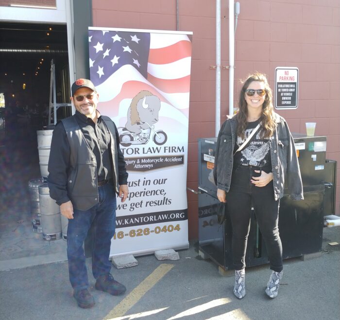 Attorneys Steve Kantor and Christina Gullo of the Kantor Gullo Law Firm stand in front of one of the firm's banners at a Bike Night event