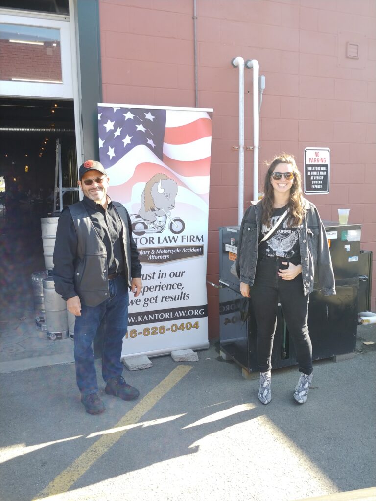 Attorneys Steve Kantor and Christina Gullo of the Kantor Gullo Law Firm stand in front of one of the firm's banners at a Bike Night event