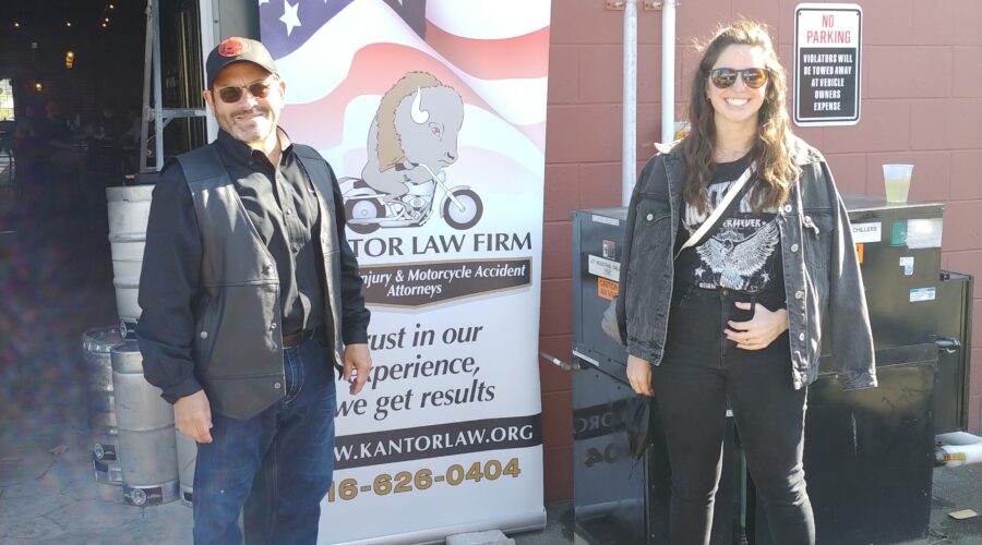 Attorneys Steve Kantor and Christina Gullo of the Kantor Gullo Law Firm stand in front of one of the firm's banners at a Bike Night event