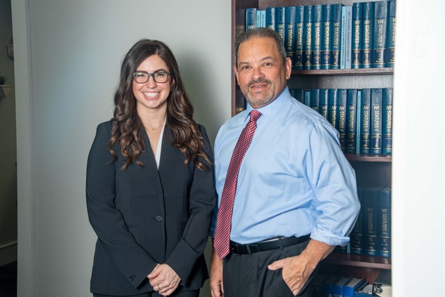 Partner Christina M. Gullo, Esq. stands near founder Steve Kantor in front of a book case full of NY Legal Statutes