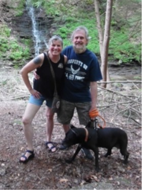 Barb Lindstrom and Paul "Flyboy" Fedorsak walking their dog in a wooded area