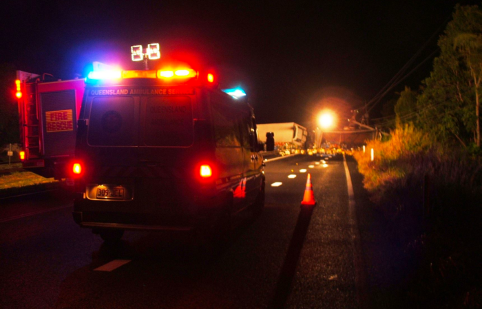 An ambulance and a fire rescue truck with flashing lights parked at the scene of a traffic incident