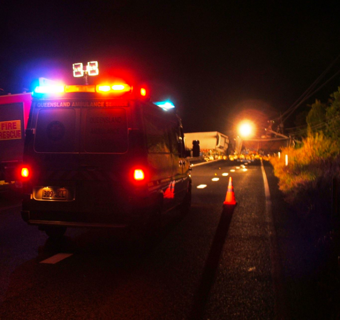 An ambulance and a fire rescue truck with flashing lights parked at the scene of a traffic incident