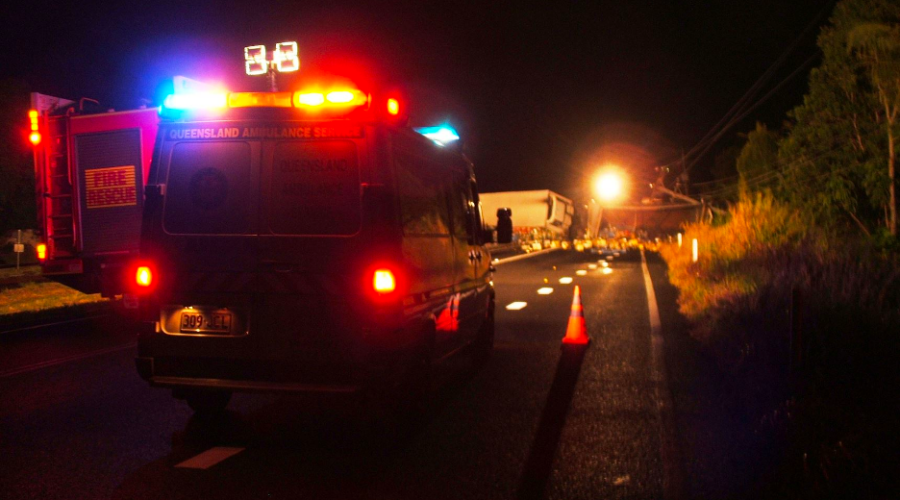 An ambulance and a fire rescue truck with flashing lights parked at the scene of a traffic incident