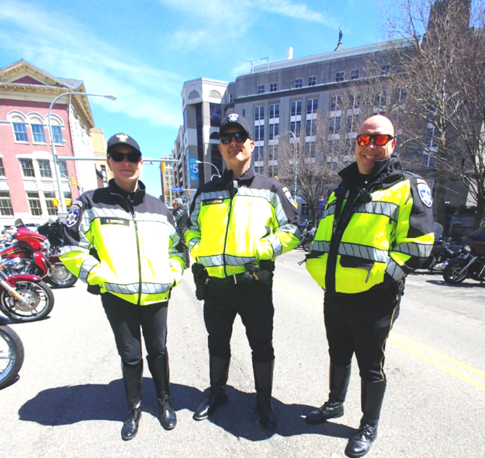 Three police officers standing on Pearl Street in downtown Buffalo, NY before they begin their duties as the outriders and escorts for the ABATE of Buffalo/Erie Awareness Run, May 15, 2023