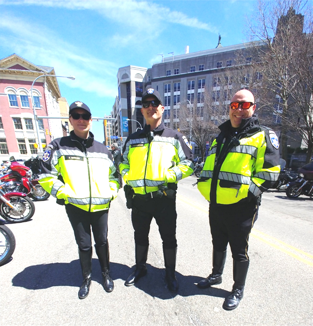 Three police officers standing on Pearl Street in downtown Buffalo, NY before they begin their duties as the outriders and escorts for the ABATE of Buffalo/Erie Awareness Run, May 15, 2023