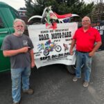 John Watson and Ed Abdo stand in front of a banner promoting the Zoar Moto-Park Reunion to be held September 26 - 28, 2025
