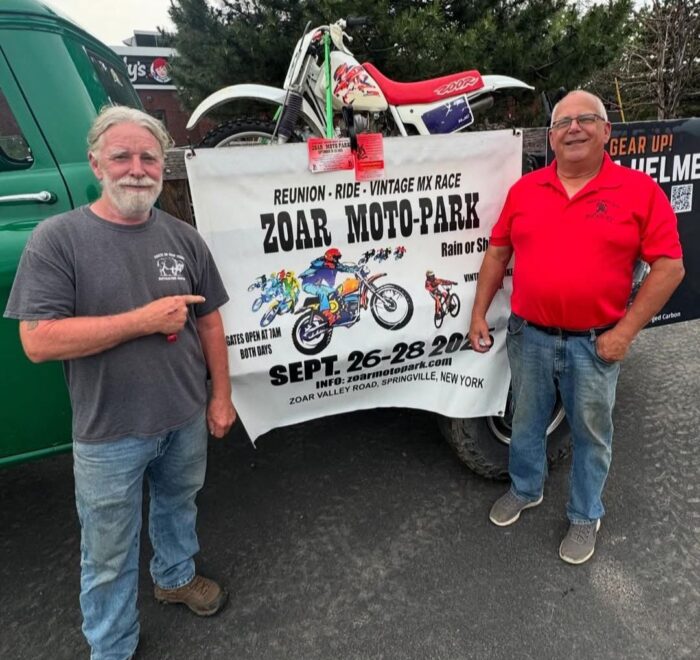 John Watson and Ed Abdo stand in front of a banner promoting the Zoar Moto-Park Reunion to be held September 26 - 28, 2025