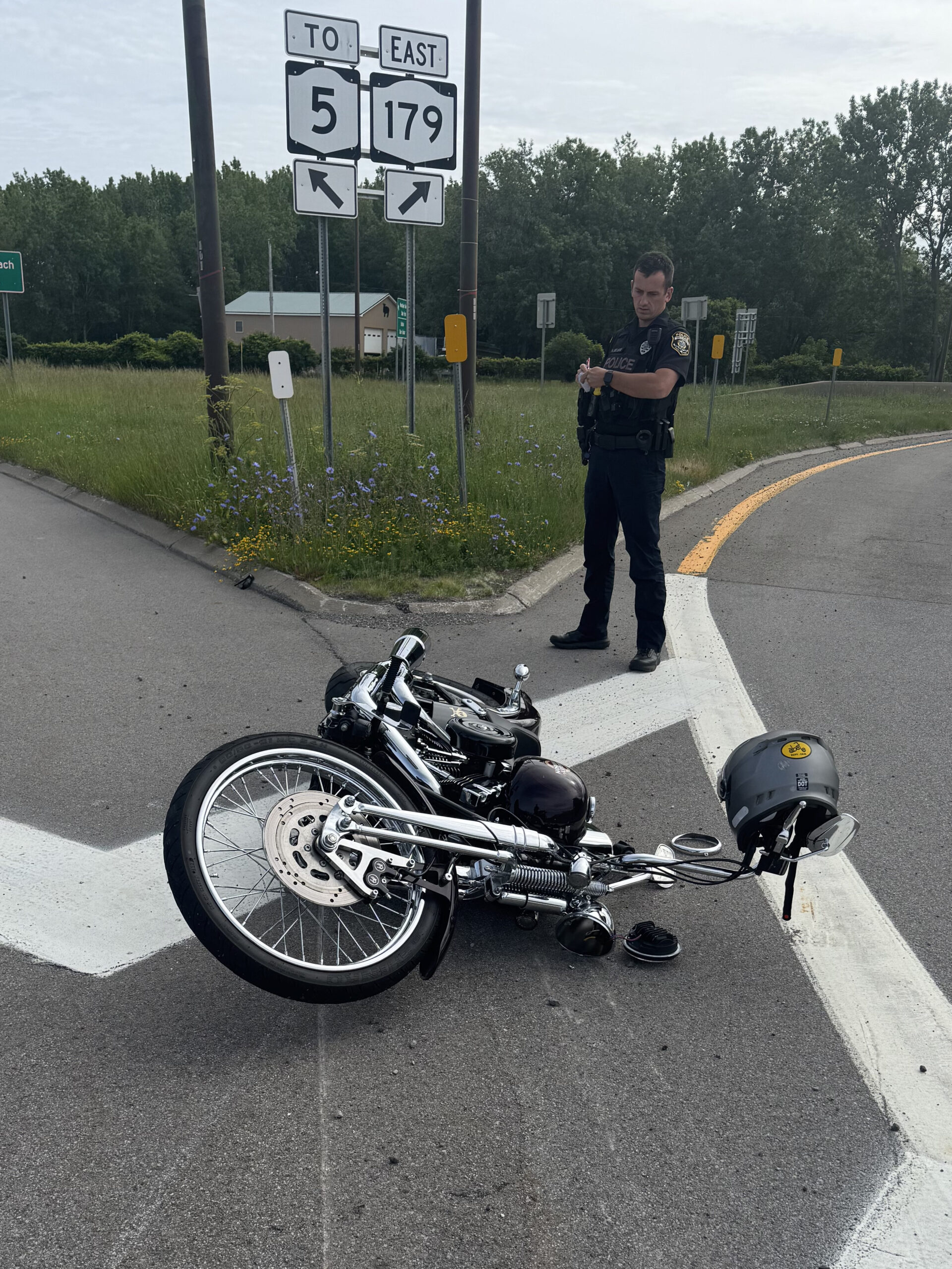 The author's 2006 Harley-Davidson Springer Softail, laying on it's left side in the traffic circle for Routes 5 & 179 in Lackawanna, NY. A police officer is filling out paperwork and looking at the bike.