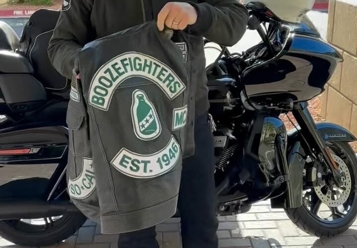 Robert Patrick stands in front of his Harley Davidson Road Glide motorcycle and shows off his perforated Boozefighters vest