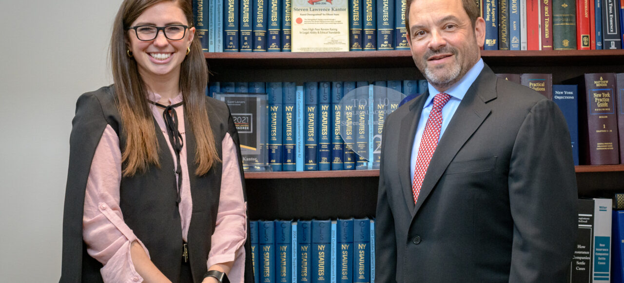 08 Attorneys Christina Gullo and Steve Kantor stand in front of a volume of legal texts with a scale resting on top of the shelves the books sit on.