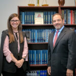 Attorneys Christina Gullo and Steve Kantor stand in front of a volume of legal texts with a scale resting on top of the shelves the books sit on.