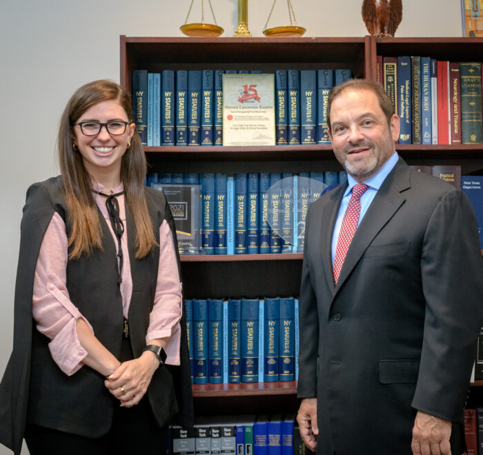 Attorneys Christina Gullo and Steve Kantor stand in front of a volume of legal texts with a scale resting on top of the shelves the books sit on.