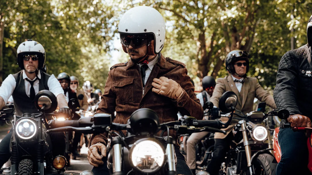 A group of motorcyclists in dapper attire sitting on their vintage motorcycles as they prepare to depart for the Distinguished Gentleman's Ride