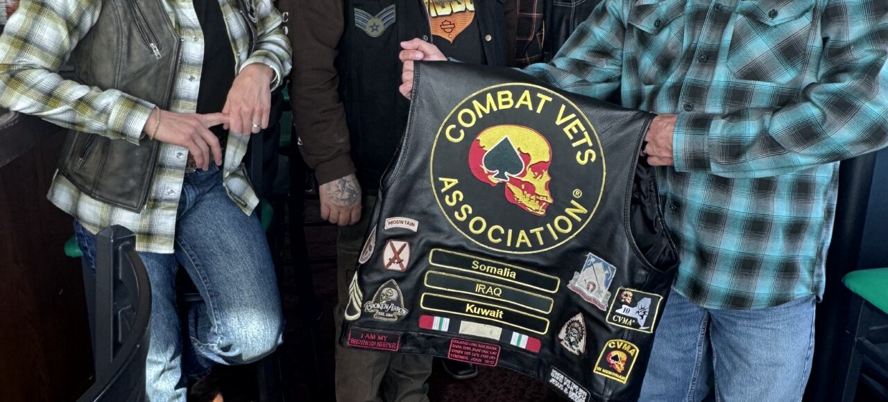 IMG_6384 Members of Combat Veterans Motorcycle Association 19-11 pose and display their patches on the back of a member's leather riding vest.