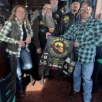 Members of Combat Veterans Motorcycle Association 19-11 pose and display their patches on the back of a member's leather riding vest.