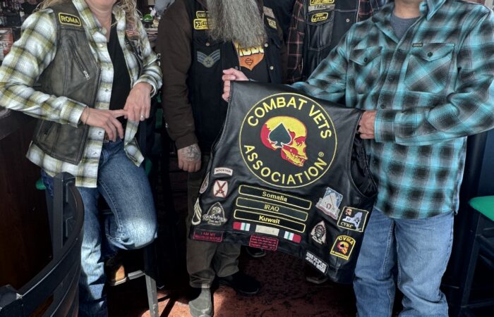 IMG_6384 Members of Combat Veterans Motorcycle Association 19-11 pose and display their patches on the back of a member's leather riding vest.