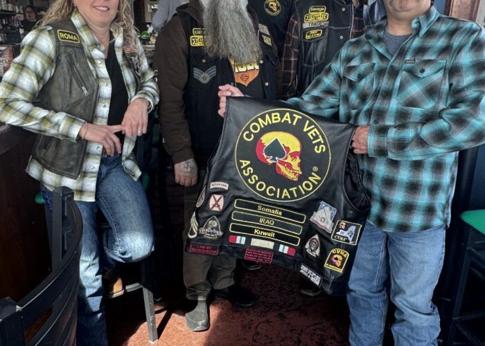 Members of Combat Veterans Motorcycle Association 19-11 pose and display their patches on the back of a member's leather riding vest.